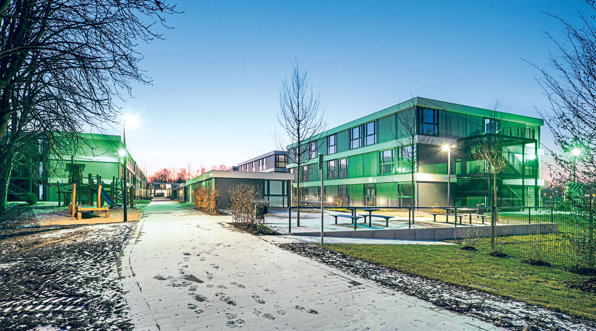Abendaufnahme von modernen smart, nachhaltig und modular gebauten Algeco-Gebäuden. Auch Büros, Schulen und Kitas  sind auf diese Weise schnell zu realisieren.(Foto: Algeco)